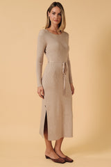 woman wearing a beige ribbed knit long sleeve dress with a side slit and a tie waist detail