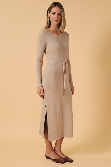woman wearing a beige ribbed knit long sleeve dress with a side slit and a tie waist detail