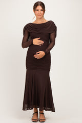 woman wearing a dark brown off-shoulder maternity dress with long sleeves and a fitted bodice, holding her baby bump