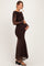 woman wearing a long sleeve brown maternity gown with ruching and a flared skirt, holding her baby bump