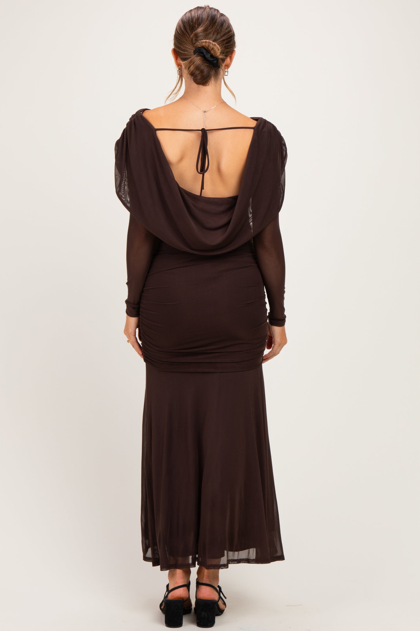 woman wearing a dark brown maternity dress with a draped back and long sleeves, showcasing a fitted silhouette