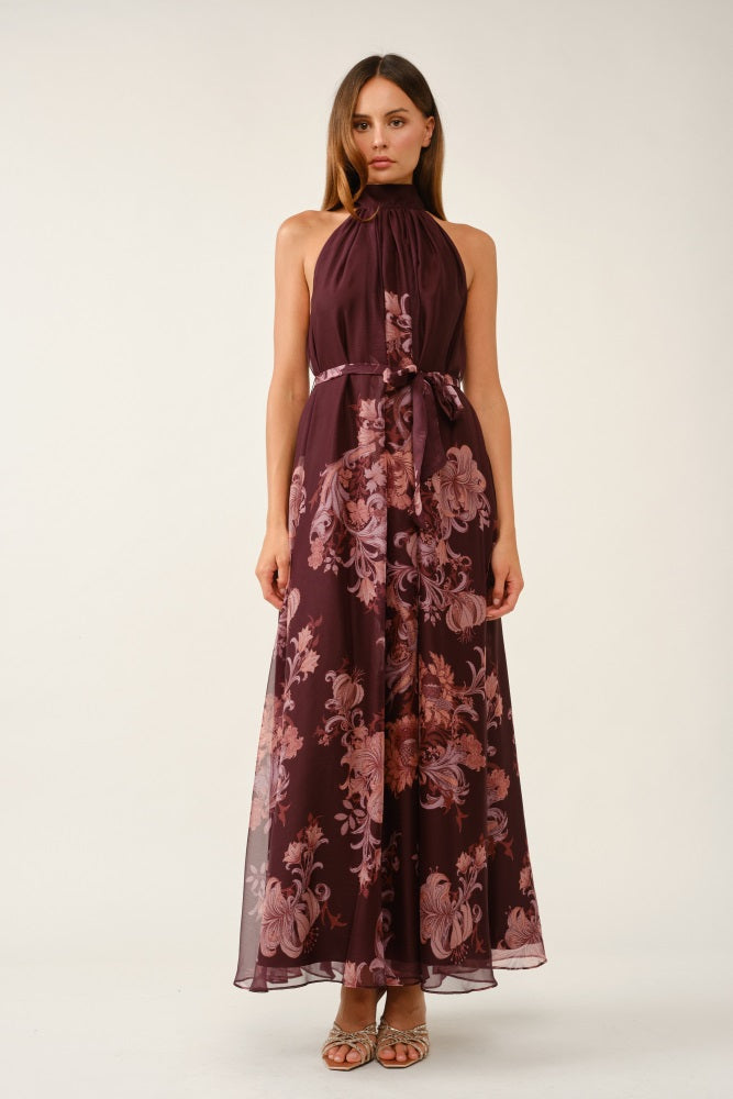woman wearing a burgundy floral maxi dress with a halter neck and a tie waist detail