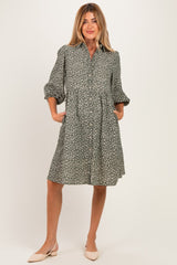 woman wearing a green floral maternity dress with puff sleeves and pockets, styled with beige flats