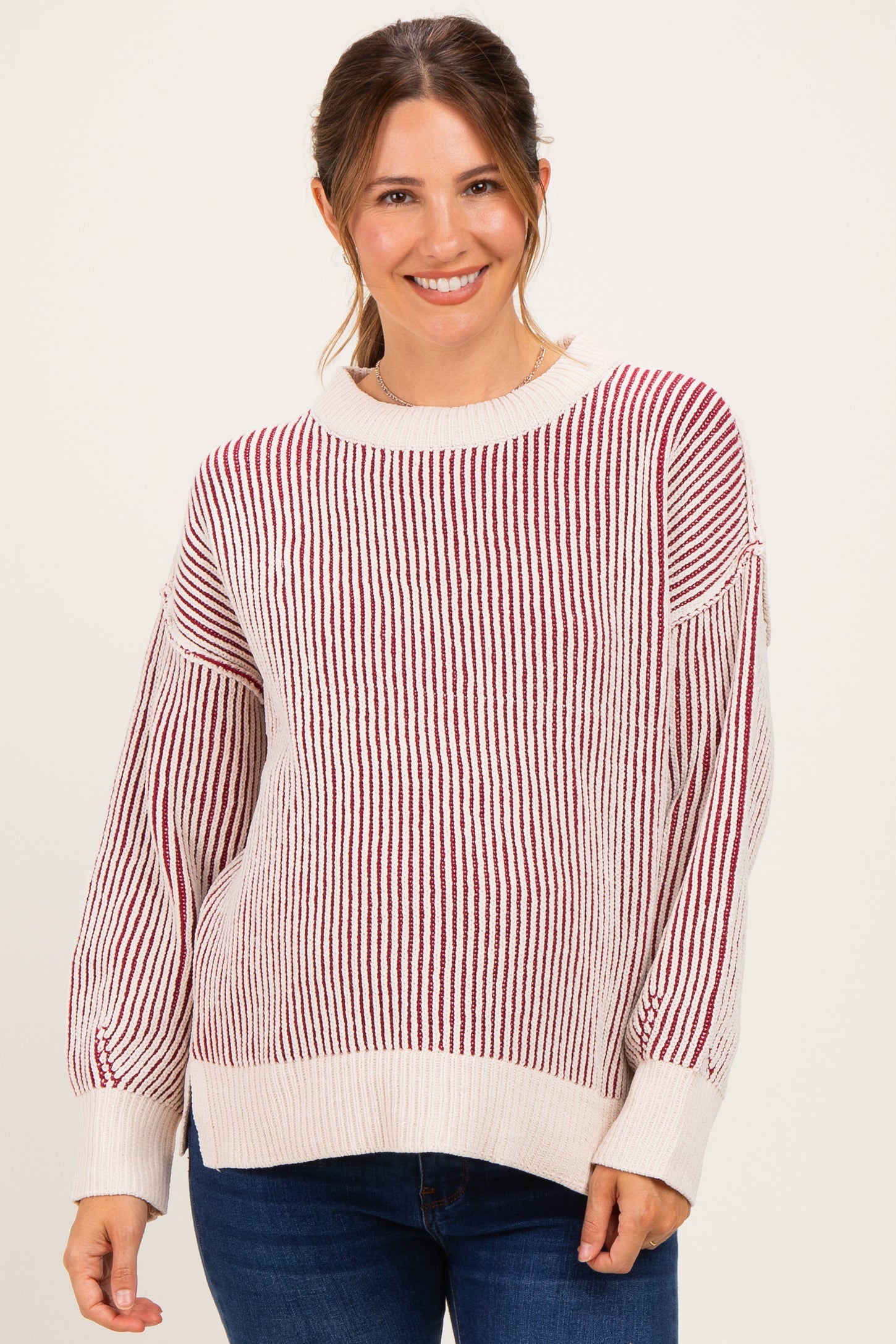 woman wearing a striped maternity sweater in cream and burgundy with balloon sleeves and a relaxed fit