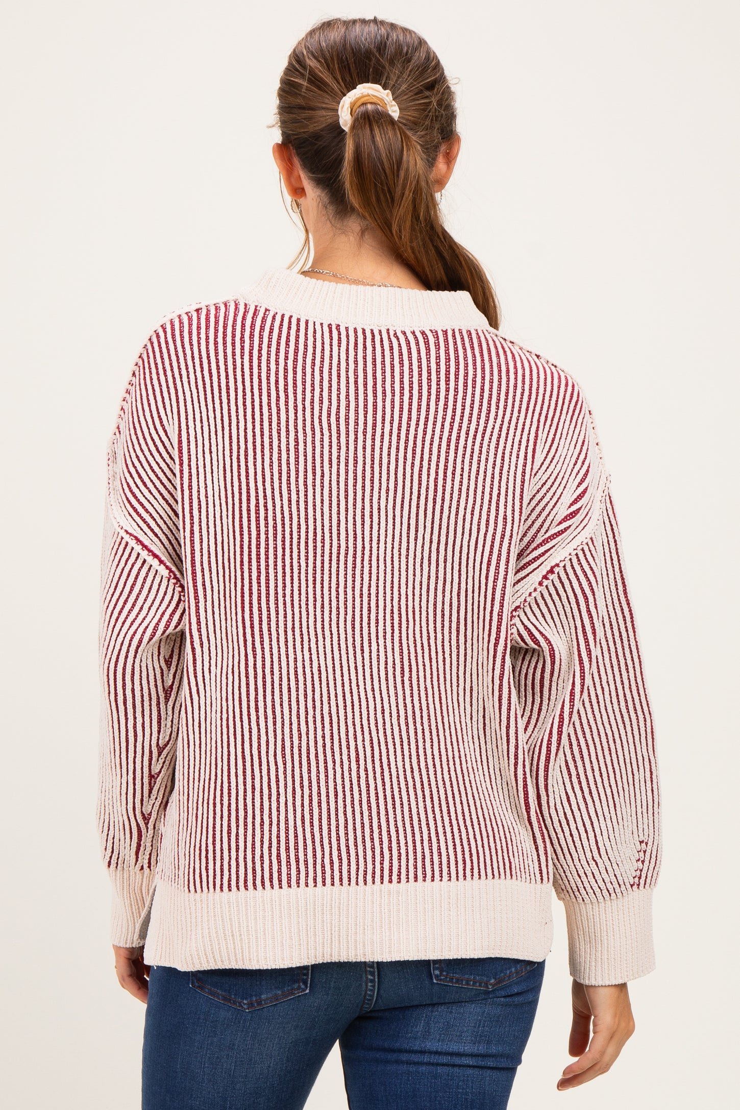 woman wearing a striped cream and red maternity sweater with a relaxed fit, seen from the back