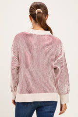 woman wearing a striped cream and red maternity sweater with a relaxed fit, seen from the back