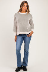 woman wearing a striped cream and gray maternity sweater with loose sleeves and blue maternity jeans