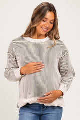 woman wearing a striped maternity sweater in neutral tones and holding her baby bump