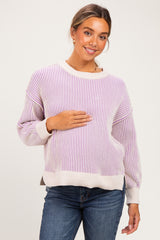 woman wearing a light purple and cream striped maternity sweater and holding her baby bump