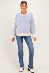 woman wearing a blue and white striped maternity sweater with balloon sleeves and light wash jeans, smiling at the camera
