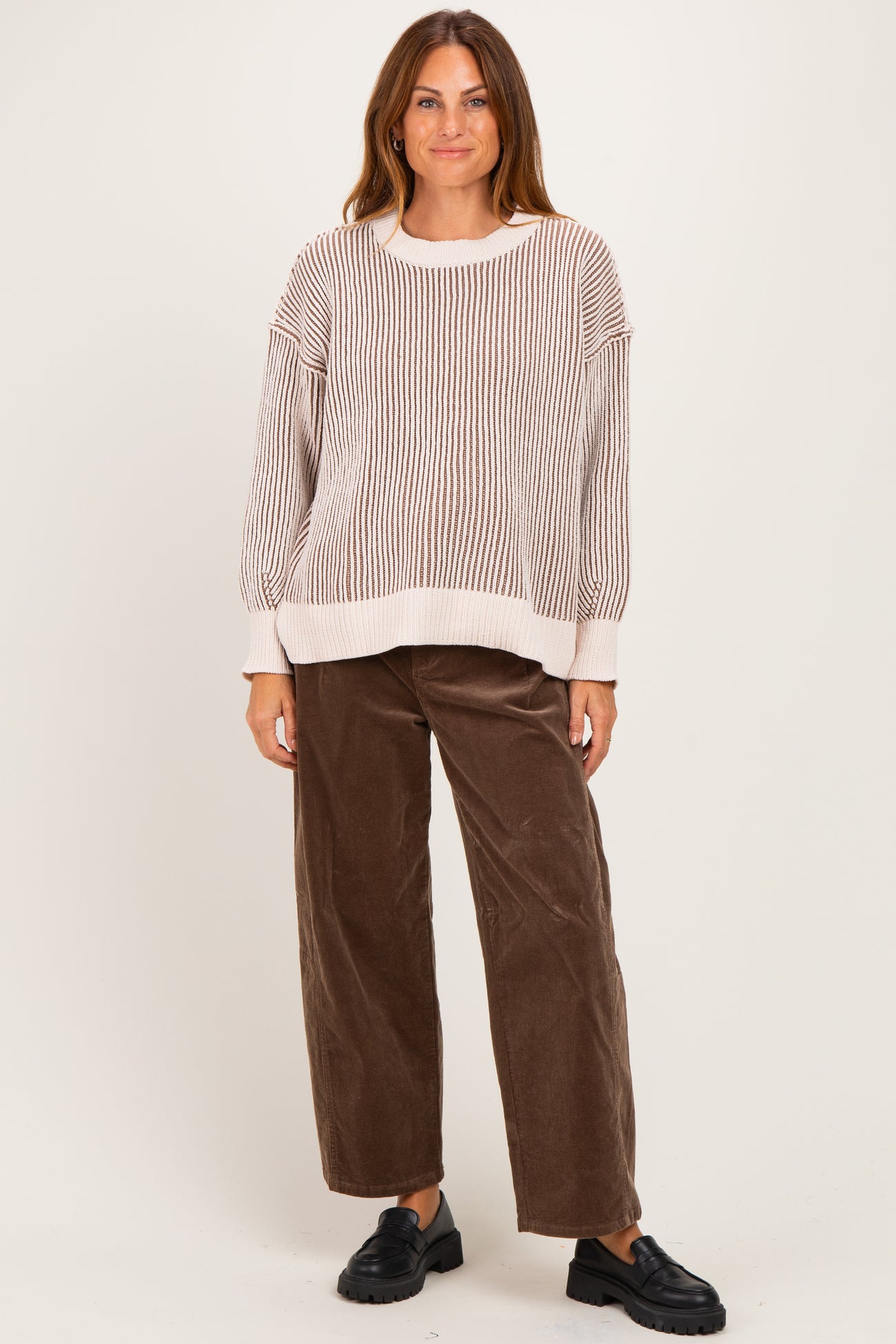woman wearing a cream and beige striped oversized sweater and brown wide-leg corduroy pants with black slip-on shoes