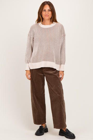 woman wearing a cream and beige striped oversized sweater and brown wide-leg corduroy pants with black slip-on shoes