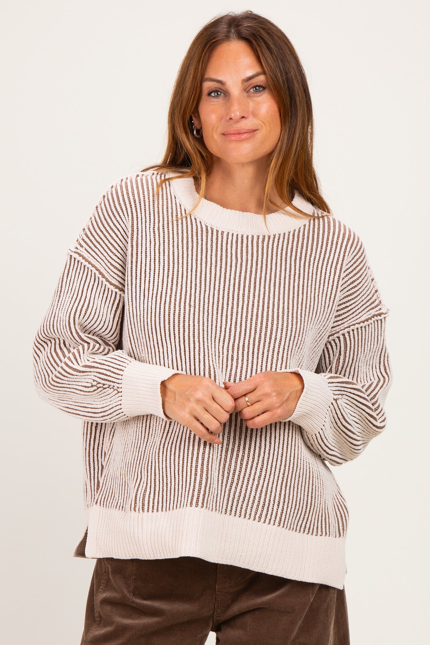 woman wearing a beige and brown striped oversized sweater with long sleeves and a relaxed fit