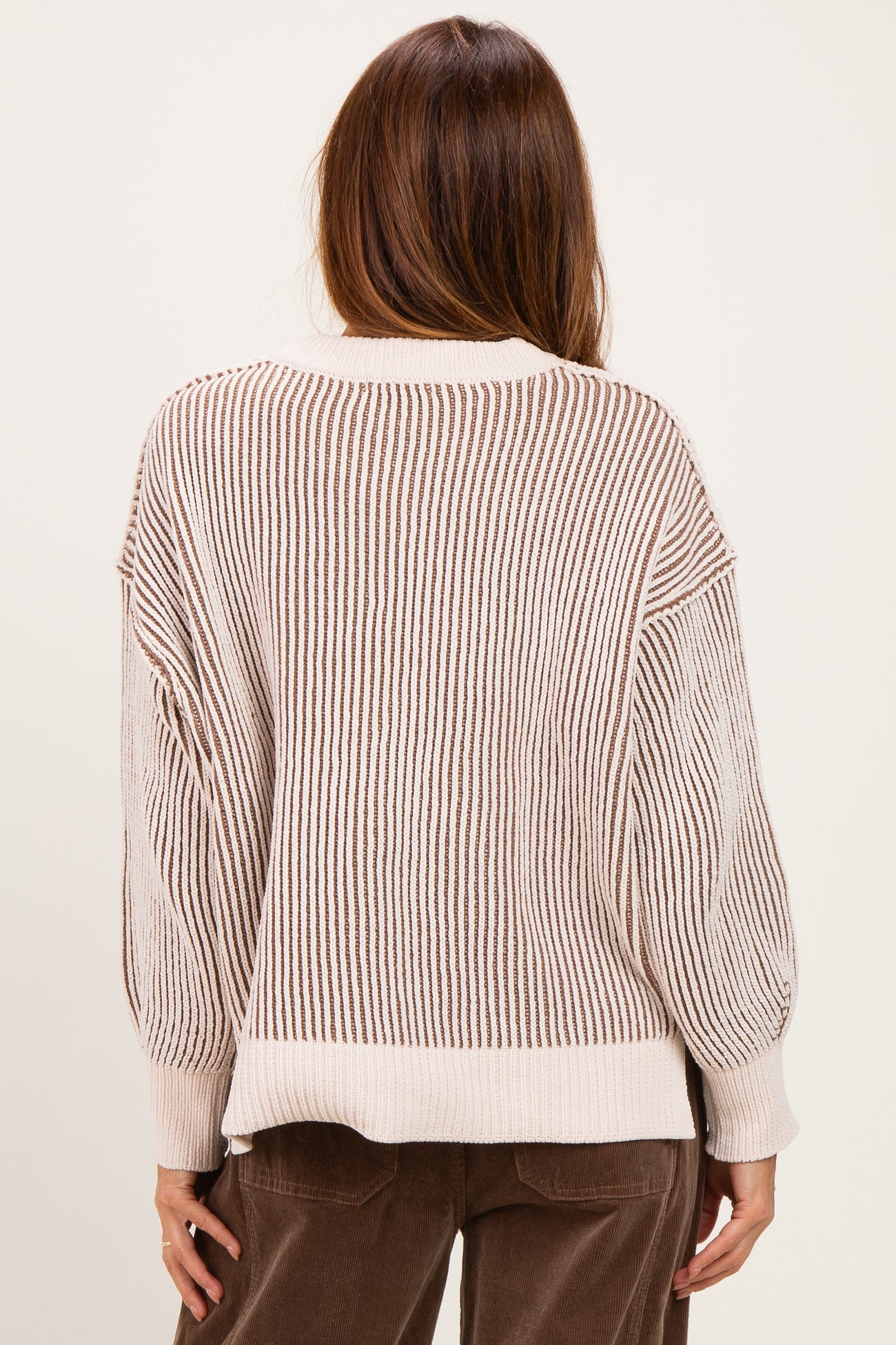 woman wearing a cream and brown striped oversized sweater, showing the back view with balloon sleeves