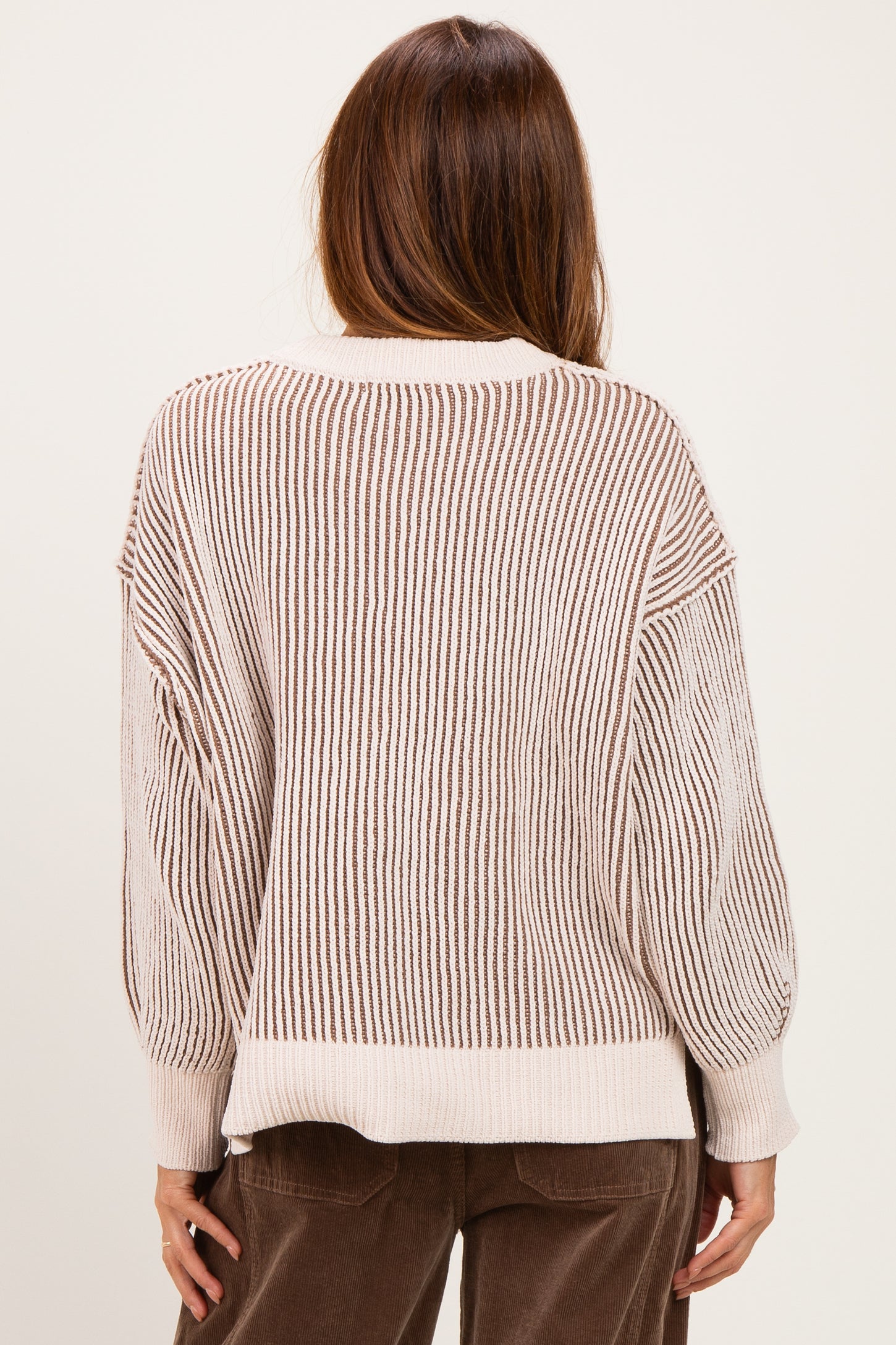 woman wearing a cream and brown striped oversized sweater, showing the back view with balloon sleeves