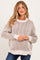 woman wearing a light beige striped knit maternity sweater with a relaxed fit and long sleeves