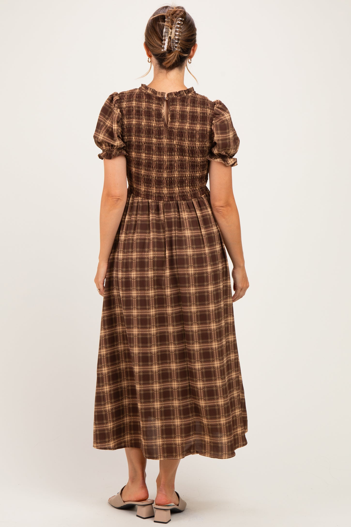woman wearing a brown plaid maternity dress with short puff sleeves and a smocked bodice, showing a baby bump
