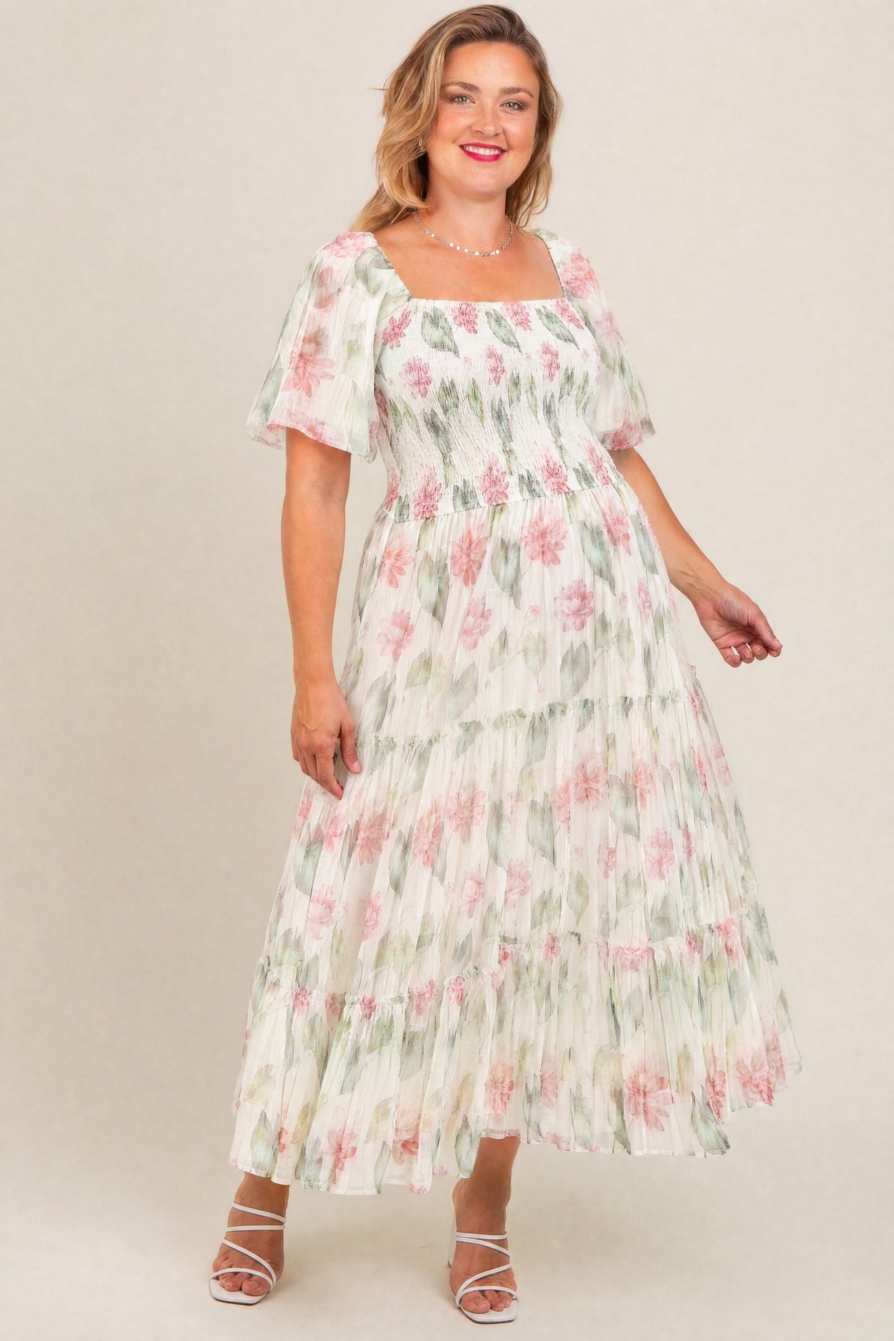 woman wearing a floral maternity plus maxi dress with square neckline and tiered skirt, smiling and showing her baby bump
