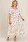 woman wearing a floral maternity plus maxi dress with square neckline and tiered skirt, smiling and showing her baby bump