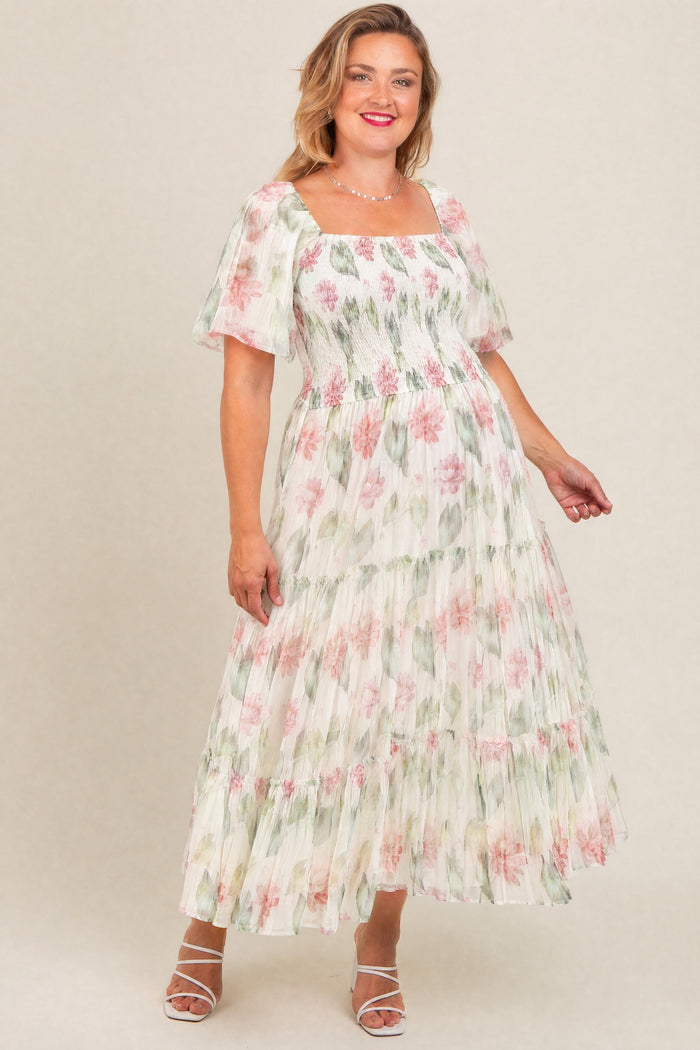 woman wearing a floral maternity plus maxi dress with square neckline and tiered skirt, smiling and showing her baby bump
