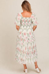 woman wearing a floral print maternity plus dress with a smocked bodice and tiered skirt, shown from the back