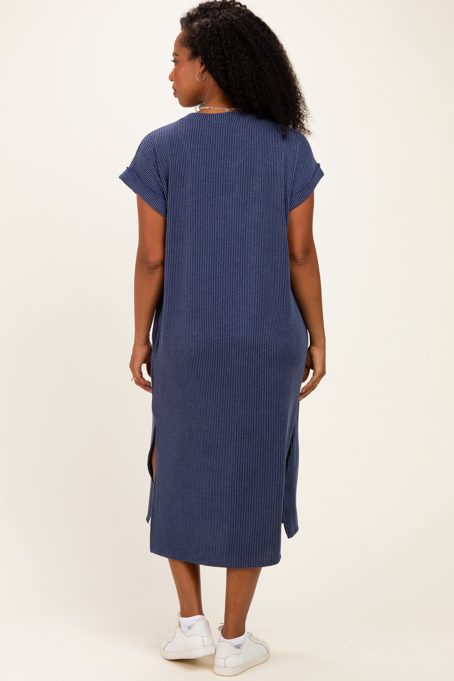 woman wearing a navy blue striped maxi dress with short sleeves and side slits, seen from the back