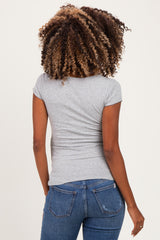 woman wearing a gray short sleeve maternity top, seen from the back with curly hair styled down