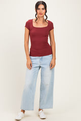 woman wearing a burgundy short sleeve ribbed top and light wash wide leg jeans with white sneakers