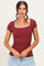 woman wearing a burgundy ribbed short sleeve top with a square neckline and scalloped edges
