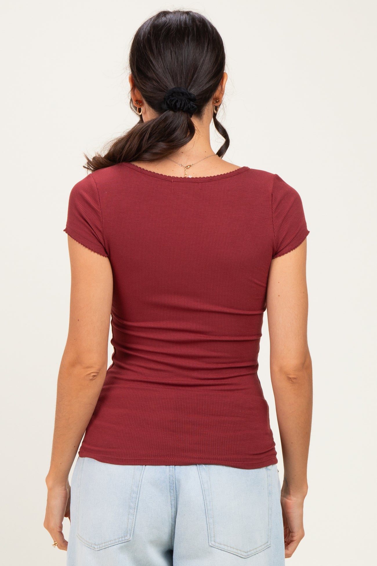 woman wearing a burgundy fitted ribbed t-shirt, seen from the back, paired with light blue jeans