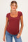 woman wearing a rust-colored short sleeve maternity top with a square neckline and a visible baby bump