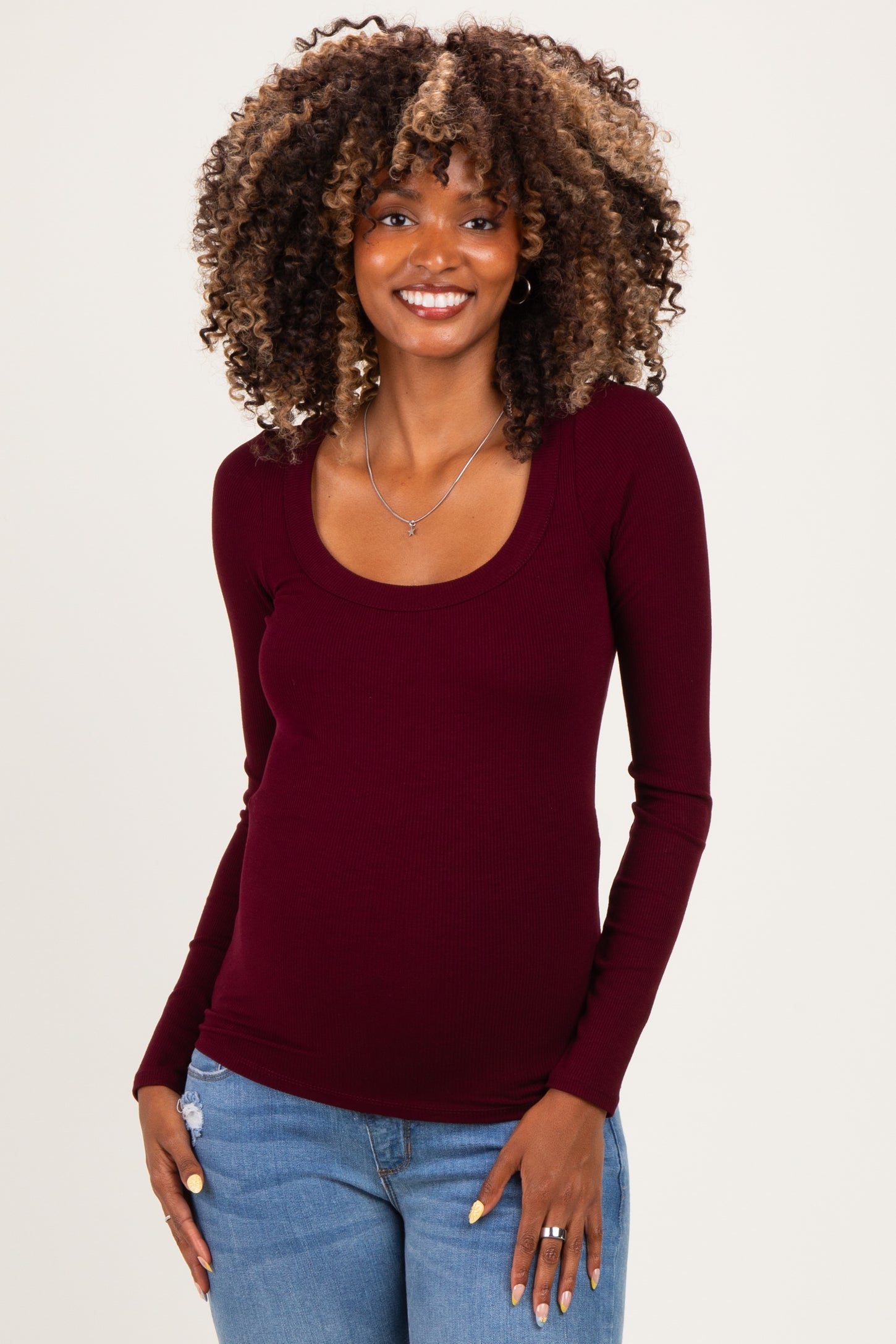 woman wearing a burgundy long sleeve maternity top with a scoop neckline and showing her baby bump