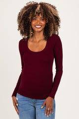 woman wearing a burgundy long sleeve maternity top with a scoop neckline and showing her baby bump