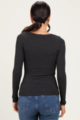 woman wearing a fitted charcoal long sleeve top with a scoop neck and ribbed texture, viewed from the back