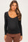 woman wearing a black long sleeve maternity top with a scoop neckline and visible baby bump