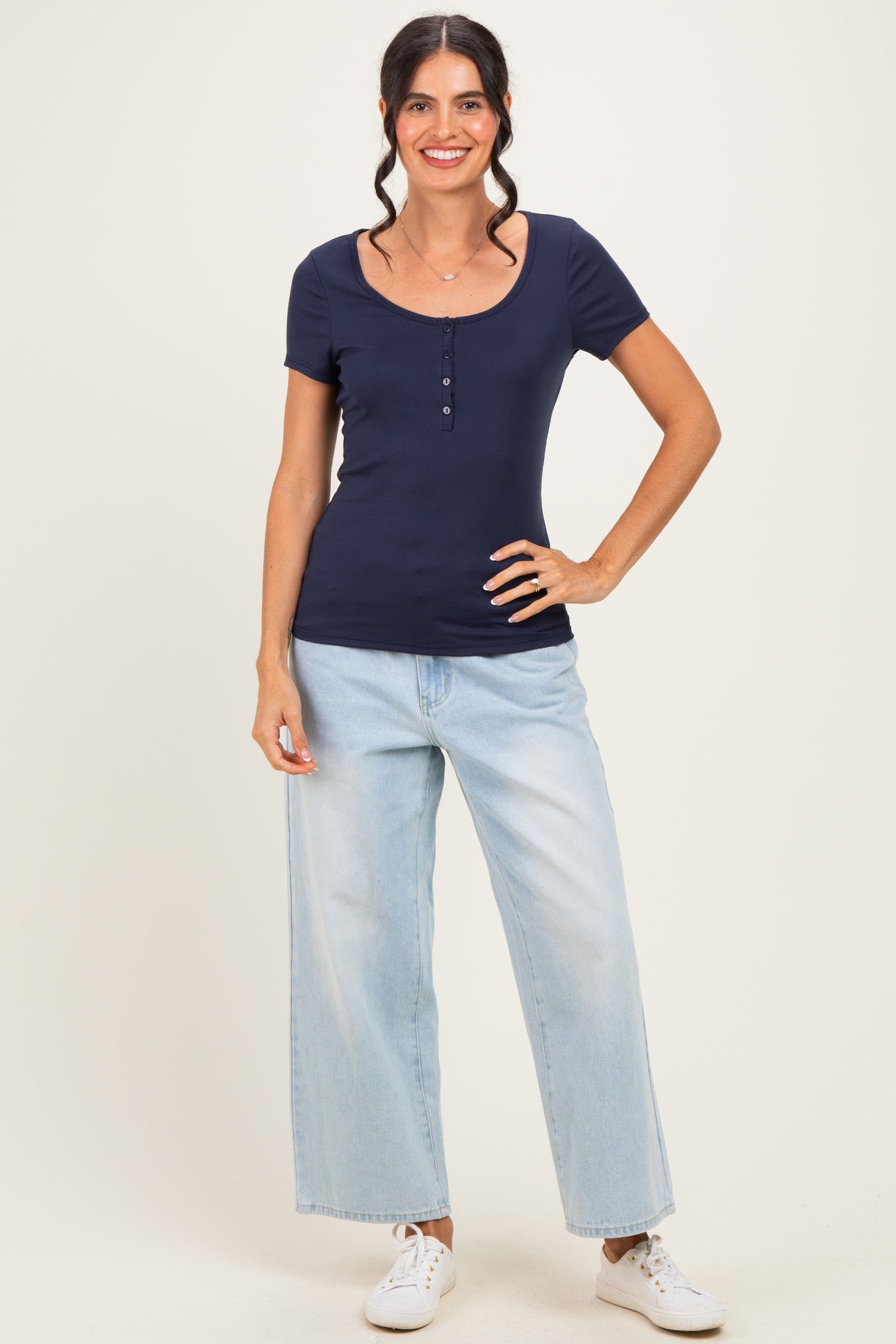 woman wearing a navy blue short sleeve fitted top with button detailing and light wash wide-leg jeans