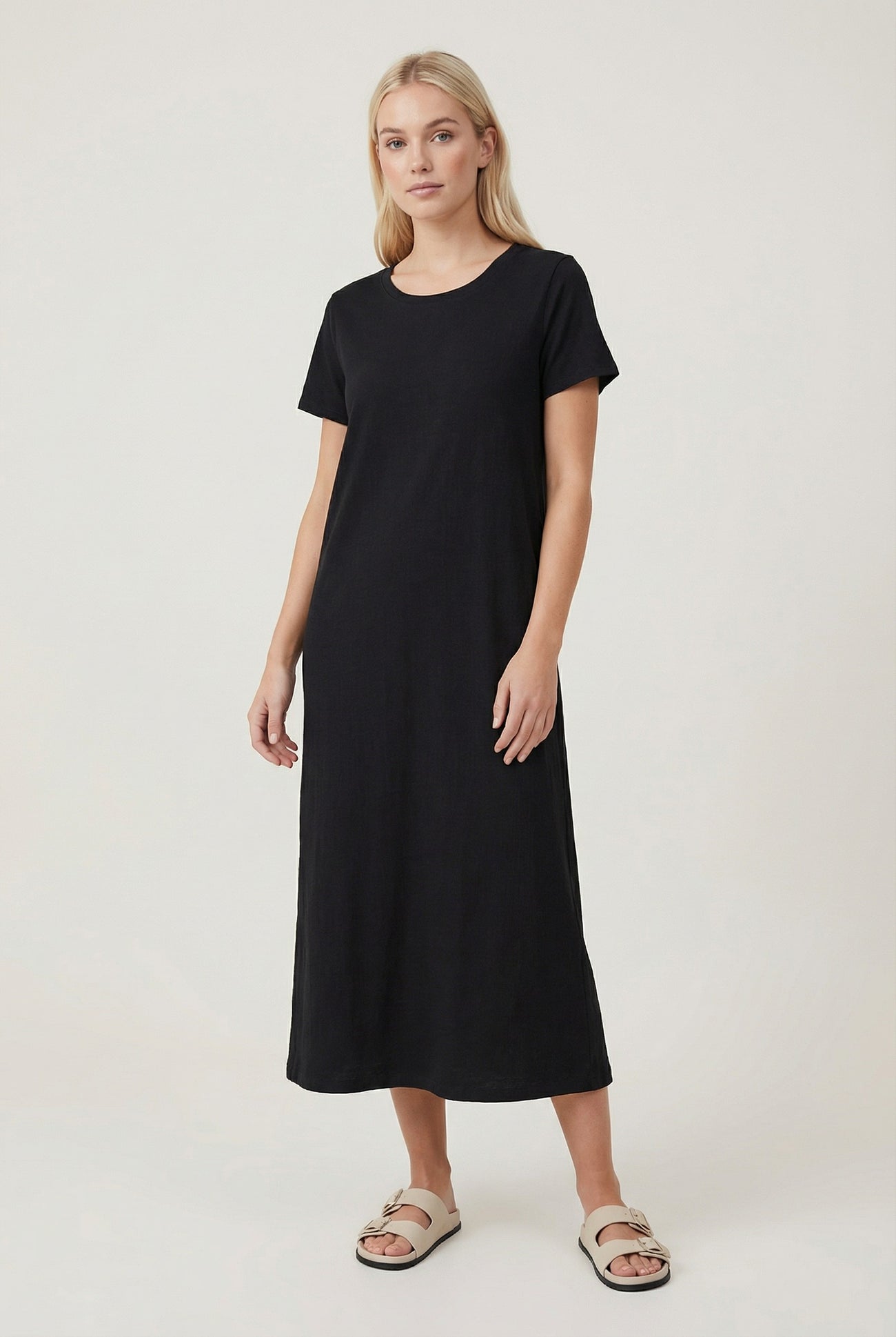 woman wearing a black short sleeve maxi dress with a relaxed fit and standing against a neutral background