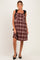 woman wearing a burgundy plaid maternity dress with black satin shoulder ties and a flared skirt
