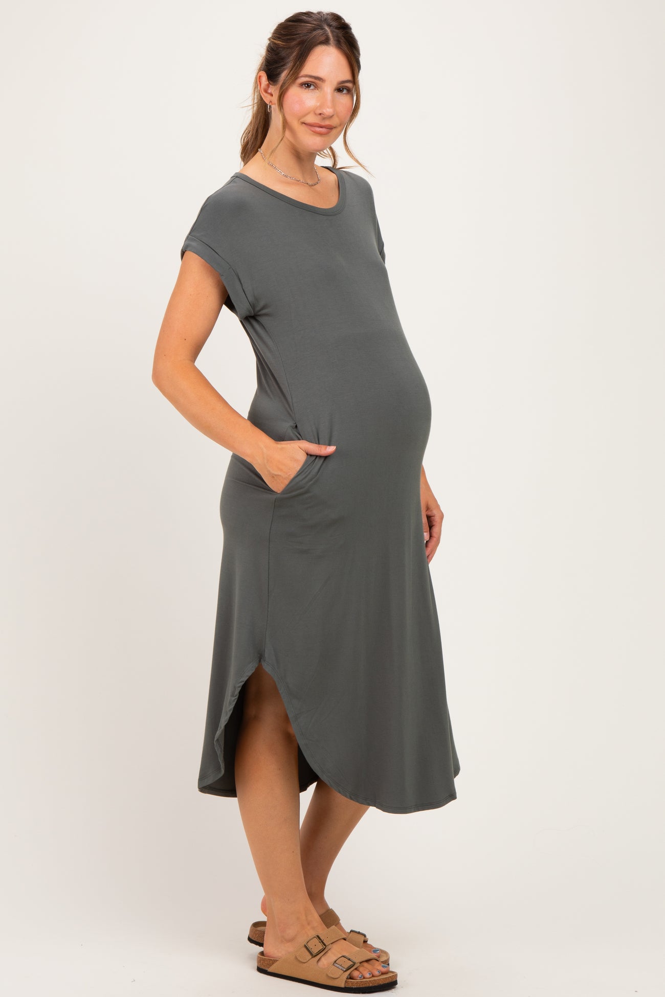 woman wearing a dark gray short sleeve maternity dress with pockets and a baby bump visible