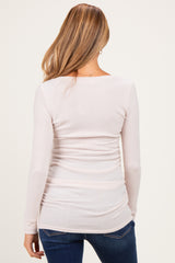 woman wearing a light pink long sleeve maternity top with gathered sides, showing a smooth silhouette from the back