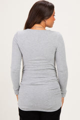 woman wearing a gray long sleeve maternity top with gathered sides and a relaxed fit, showing a subtle baby bump