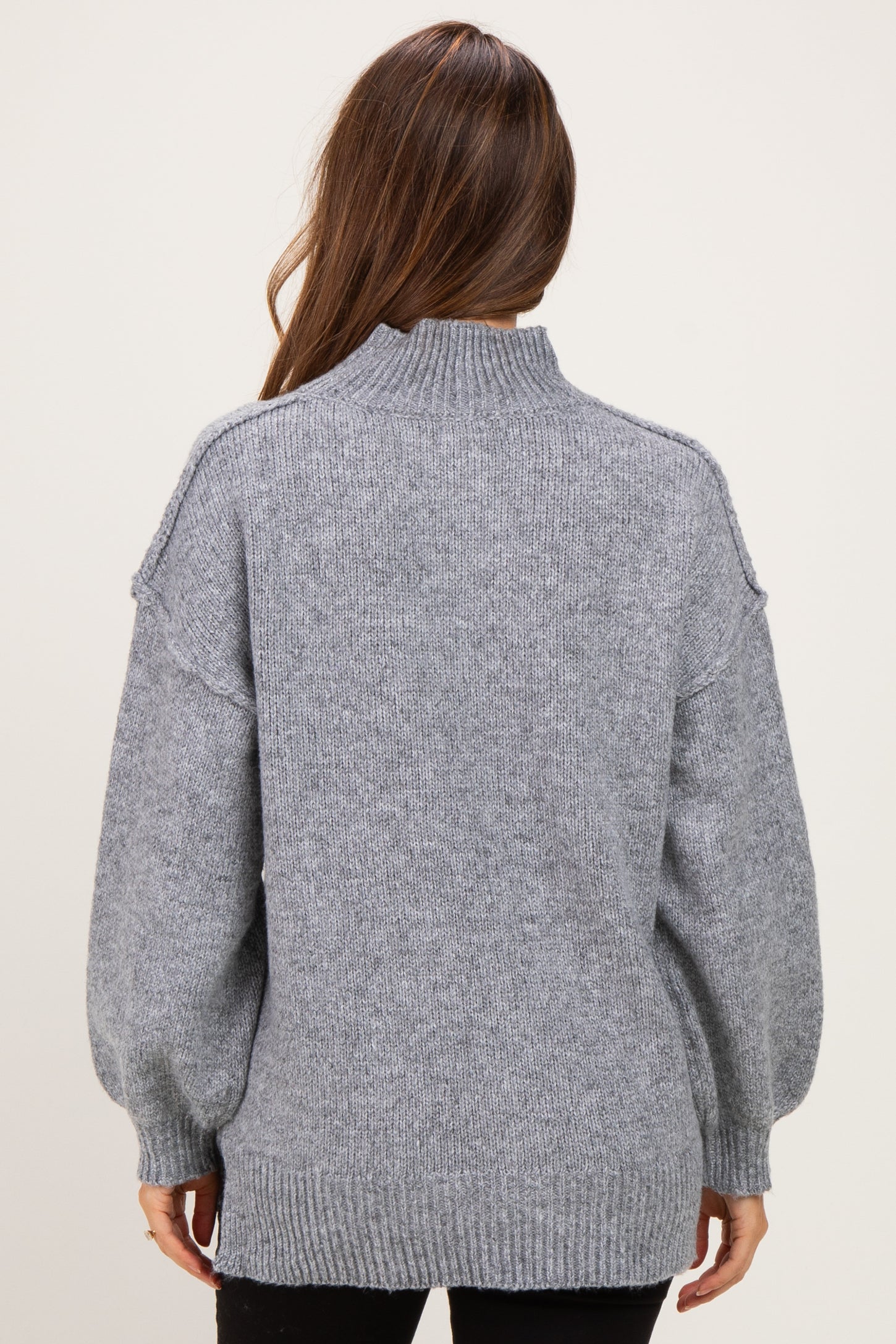 woman wearing a gray maternity sweater with a high neck and balloon sleeves, shown from the back