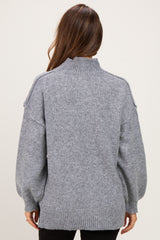 woman wearing a gray maternity sweater with a high neck and balloon sleeves, shown from the back