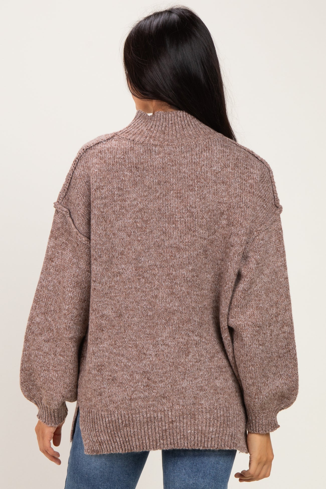 woman wearing a brown oversized knit sweater with a high neckline and balloon sleeves, viewed from the back