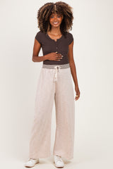 woman wearing a dark brown maternity short sleeve top and light beige wide-leg maternity pants