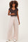 woman wearing a dark brown maternity short sleeve top and light beige wide-leg maternity pants