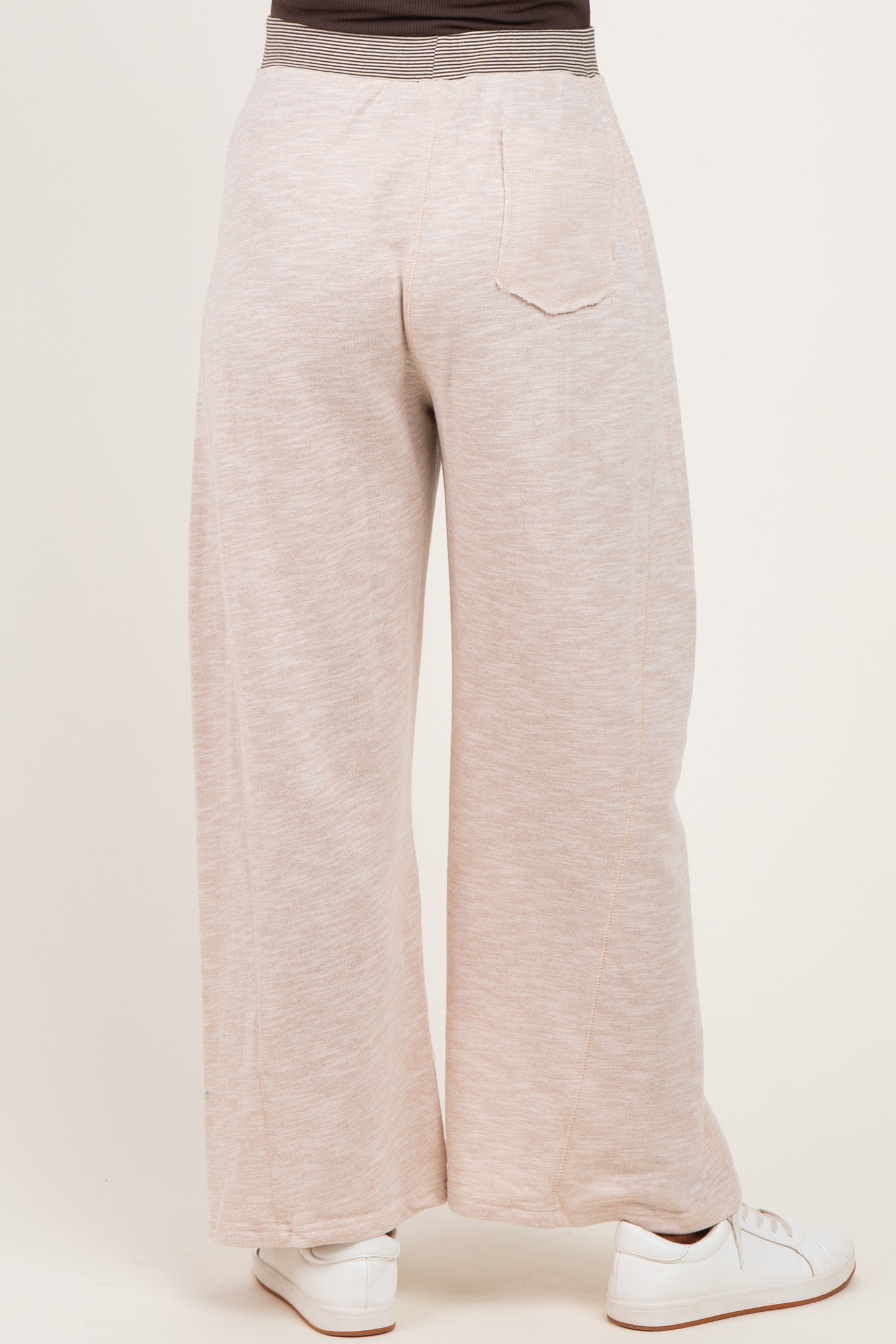 woman wearing light taupe maternity wide-leg pants, view from the back, paired with white sneakers