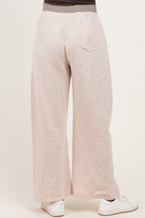 woman wearing light taupe maternity wide-leg pants, view from the back, paired with white sneakers