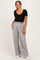 woman wearing a black ribbed maternity top and grey wide-leg pants with a drawstring waistband