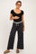 woman wearing a black ribbed maternity top and gray wide-leg maternity pants, holding her baby bump